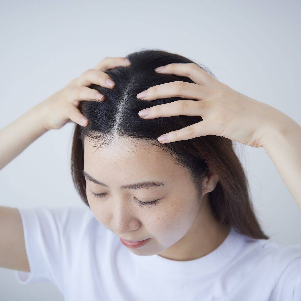 女性がMy.Supporter ヘアエッセンスを使用し、頭皮をマッサージしている様子。IFMC.配合で頭皮にうるおいを与え、健やかな髪へ導くヘアケア製品。