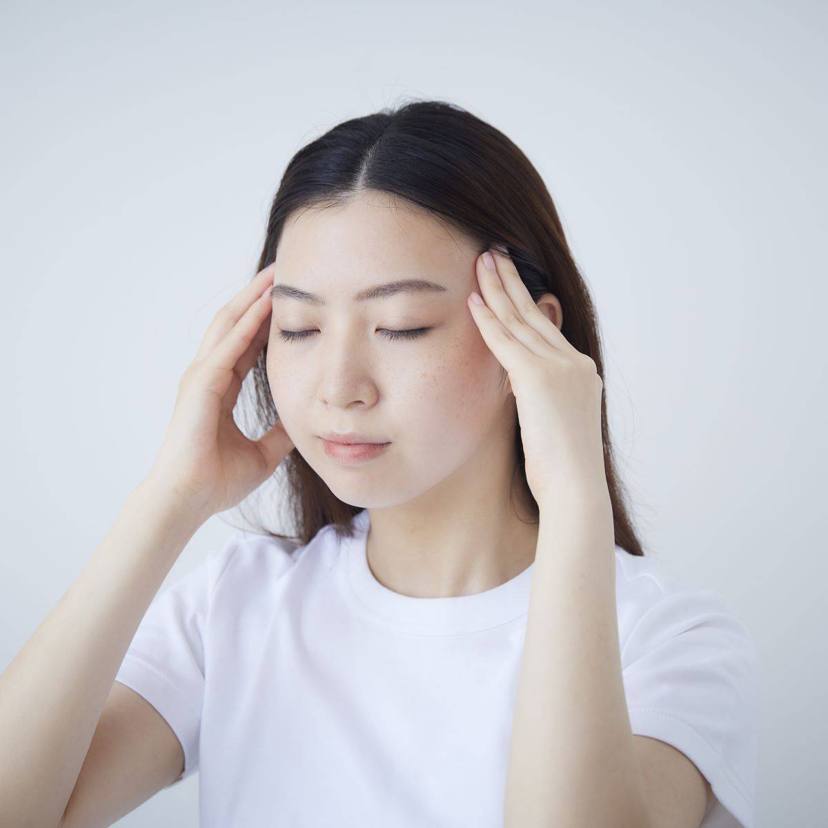 目を閉じてこめかみをマッサージする女性。My.Supporter ヘアエッセンスで頭皮ケアをサポートし、健やかな髪へ導く美容習慣。